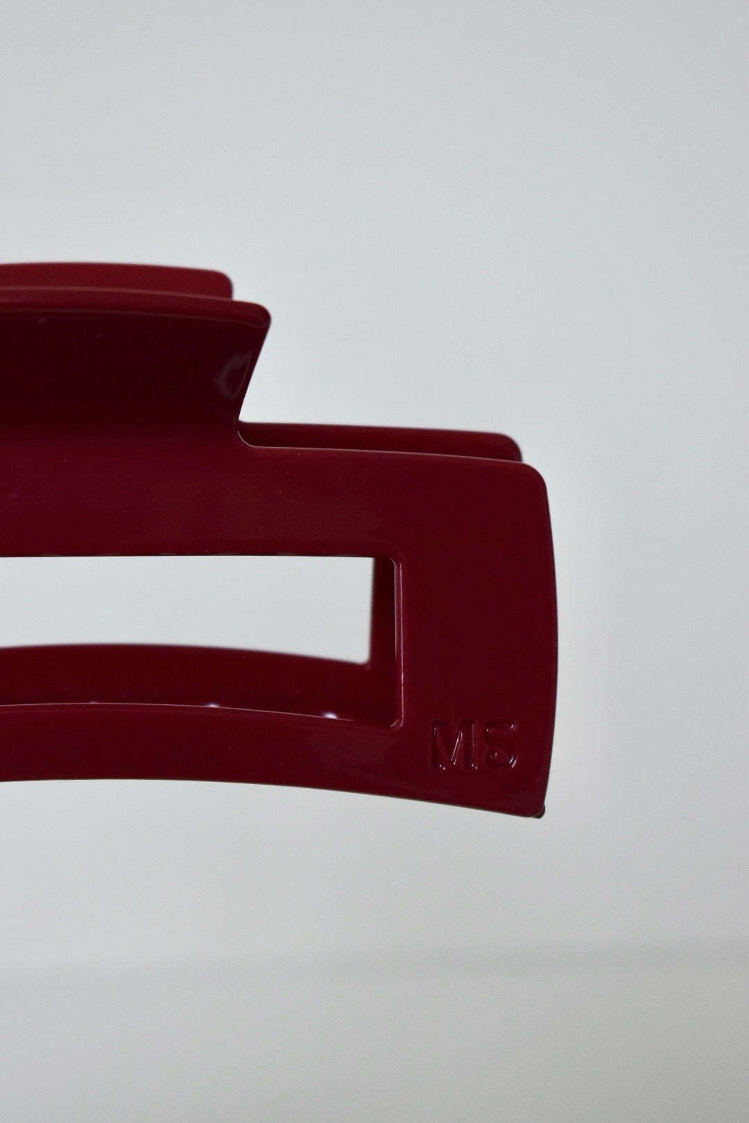 Detail van bordeauxrode acetaat haarklem – glanzende afwerking met gladde randen