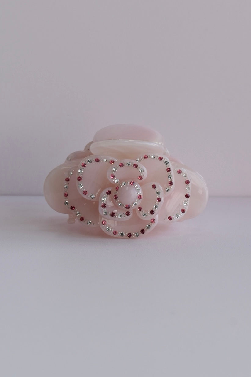 Detailfoto van roze haarklem met sierlijke bloem en subtiele glitters, een stijlvol accessoire voor dagelijks gebruik of speciale gelegenheden.