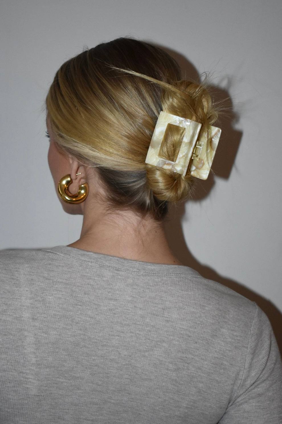 Zijaanzicht van vrouw met blond haar en matte botergele haarklem, geschikt voor dagelijks gebruik.