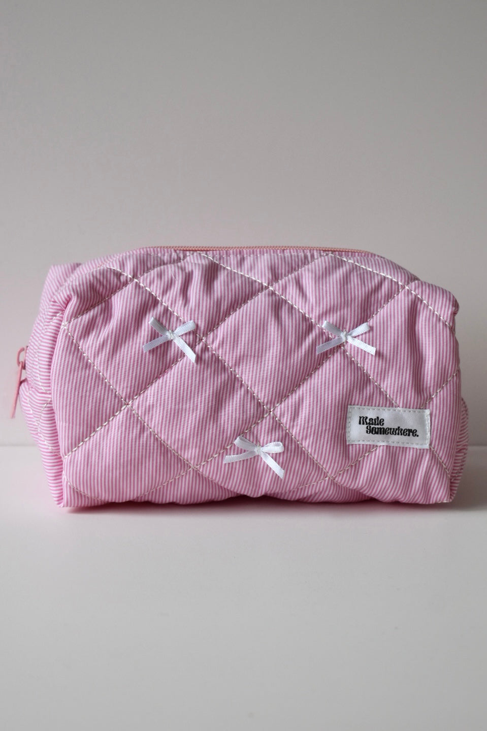 Detail van zachtroze make-up pouch met verticale strepen, praktisch én trendy.