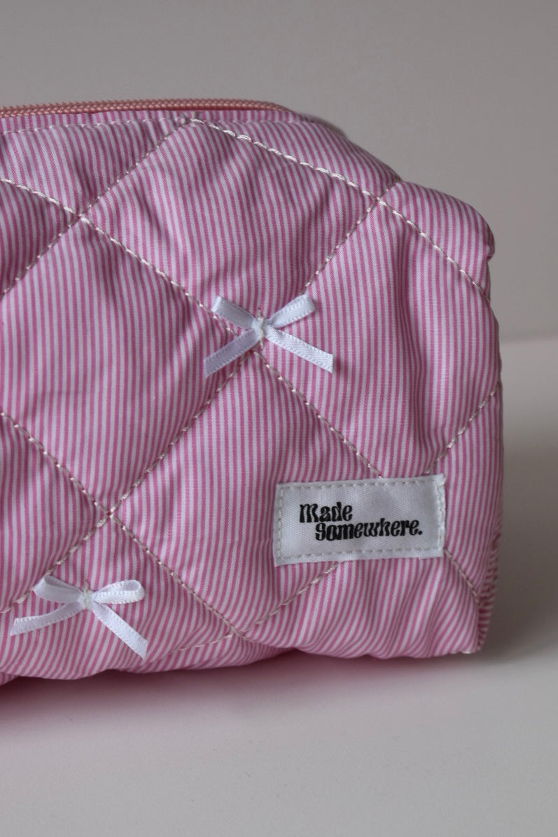 Compact roze toilettasje met strikjes, perfect voor in je handtas of op reis.