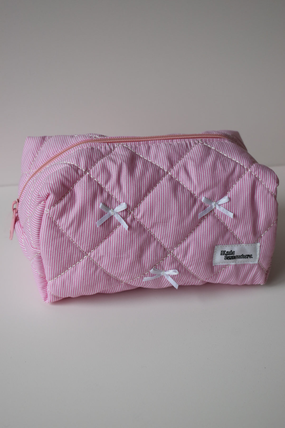 Roze gestreept make-up tasje met minimalistische look en strikjes, geschikt voor dagelijks gebruik.