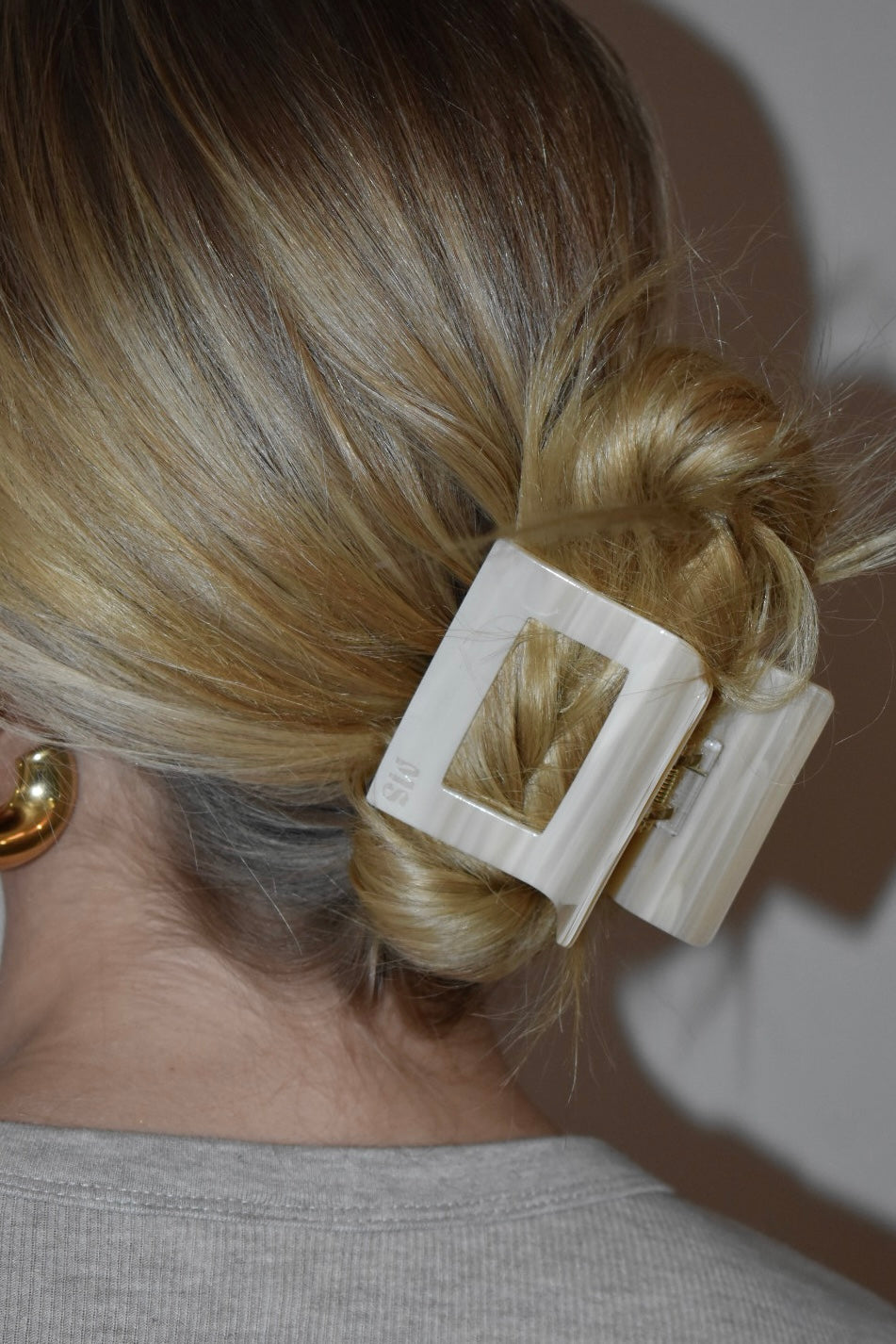 Zijaanzicht van vrouw met blond haar en beige haarklem, geschikt voor dagelijks gebruik."