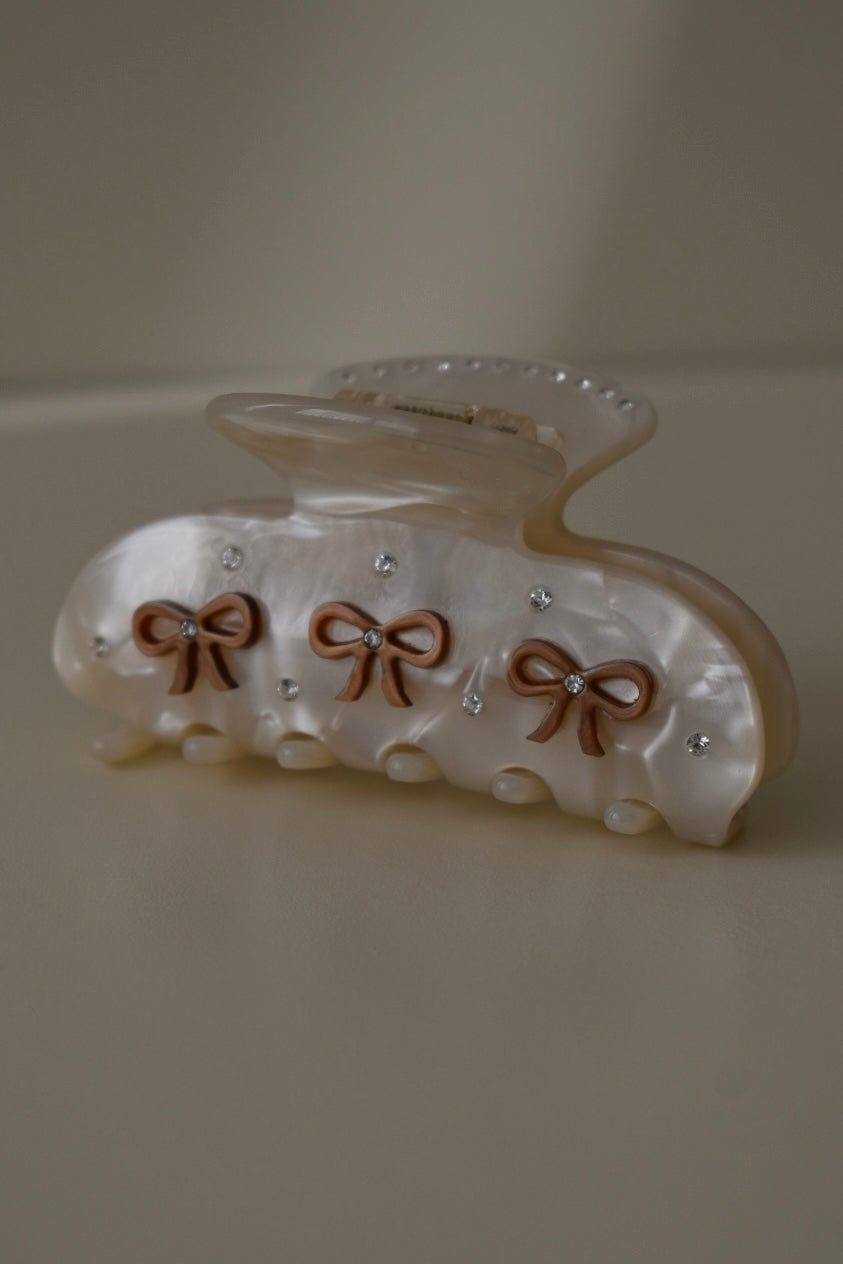 Close-up van beige haarclip met strikjes met zilveren steentjes – elegante afwerking