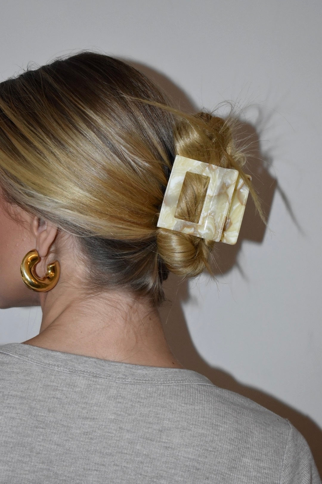Model met opgestoken haar draagt botergele haarklem van acetaat, perfect voor een dik haar.