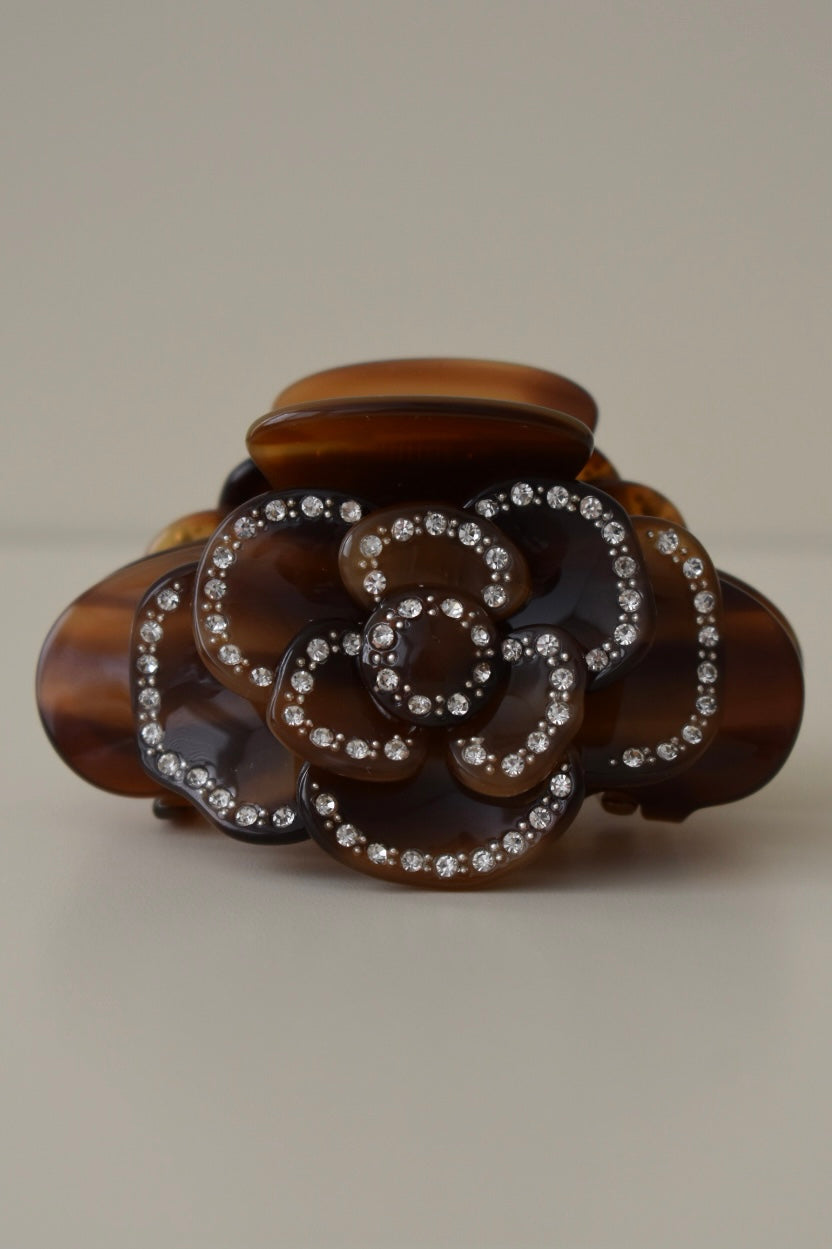 Close-up van roosdetail met zilveren steentjes op bruine haarklem – elegante afwerking