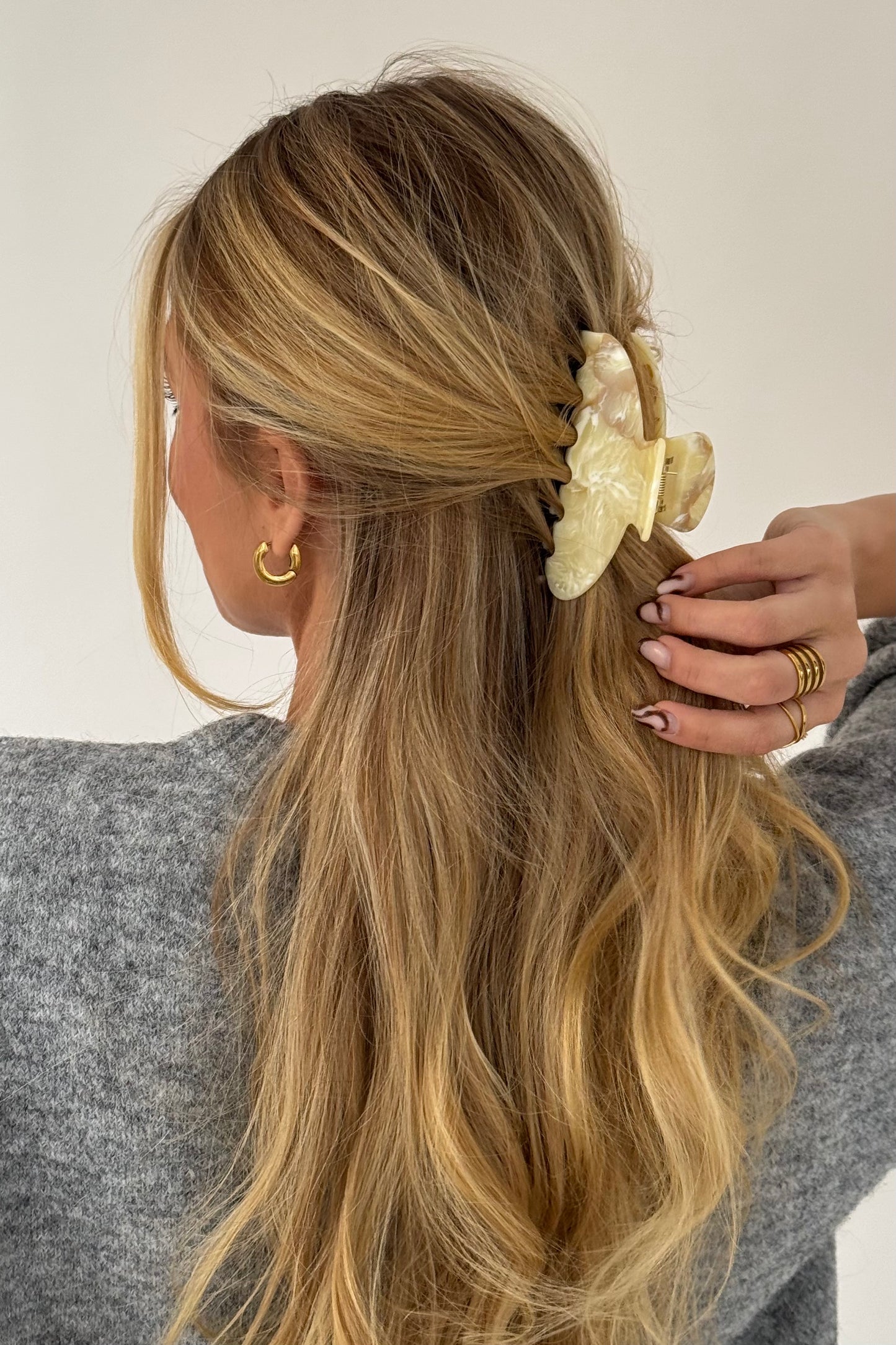 Model met losjes opgestoken haar draagt honingkleurige haarklem van glanzend acetaat, een stijlvolle everyday look.